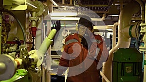 Marine engineer inspecting ship's engine in engine control room