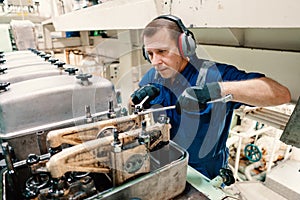 Marine engineer officer controlling vessel enginesand propulsion in engine control room ECR