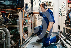 Marine engineer officer controlling vessel enginesand propulsion in engine control room ECR