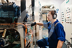 Marine engineer officer controlling vessel enginesand propulsion in engine control room ECR