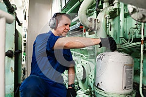 Marine engineer officer controlling vessel enginesand propulsion in engine control room ECR