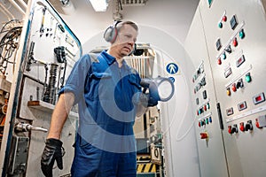 Marine engineer officer controlling vessel enginesand propulsion in engine control room ECR