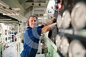 Marine engineer officer controlling vessel enginesand propulsion in engine control room ECR photo