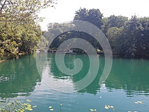 A marine green body of water at rest at the bottom of the great krka waterfalls.