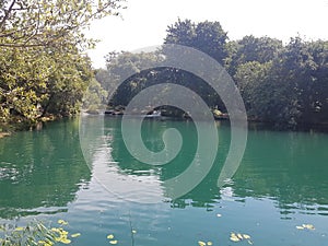 A marine green body of water at rest at the bottom of the great krka waterfalls.