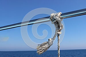 Marine Knot Detail Stainless Steel Boat Railing. Marine Fender Knot Around Boat Lee. Close-up nautical knot rope on sail boat