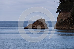 Marine landscape with sea, rocky outcrop and ship on background, Waihi, Waikato region, New Zealand