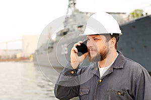 Marine male engineer talking by VHF walkie talkie near vessel in background. photo