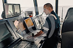 Marine navigational officer is using laptop or notebook at sea