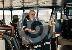 Marine navigational officer is using laptop or notebook at sea