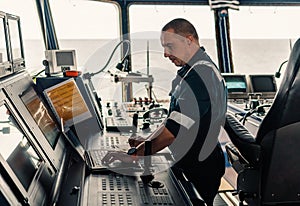 Marine navigational officer is using laptop or notebook at sea