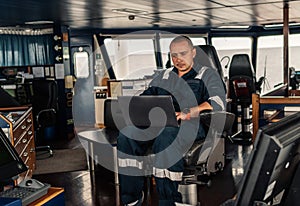 Marine navigational officer is using laptop or notebook at sea