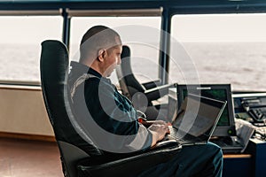 Marine navigational officer is using laptop or notebook at sea