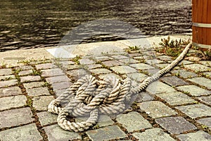 Marine rope tied knot lying on the sidewalk near the pier.