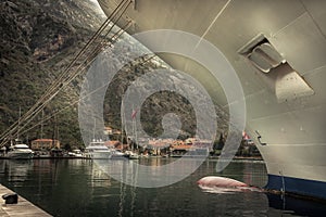 Marine sea port with moored cruise nautical vessel in medieval Kotor bay in Montenegro in overcast rainy autumn day