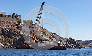 Marine work near Mykonos island port. Cyclades Greece. Construction machine, crane and barge on site