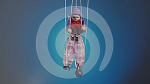 Marionette clown hanging on strings. A rag doll in a purple suit and hat, with a red bow, nose and makeup. Soft doll