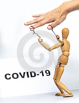 Marionette in human hand with Covid-19 inscription