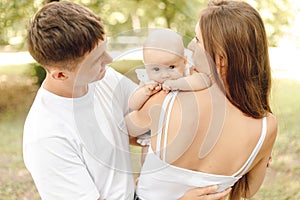 Marital and parental love and tenderness. Mom, dad and newborn baby in park on sunny summer day.