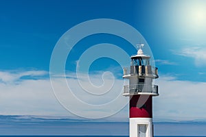 Maritime lighthouse on cliff with blue sea in the background