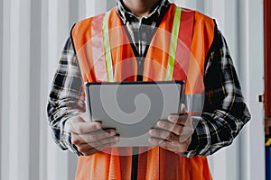Maritime logistics manager in high-visibility vest holding a tablet