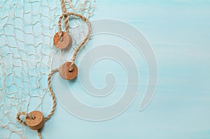 Maritime nautical blue and turquoise wooden background with a fishing net.