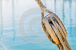 Maritime nautical wooden pulley with ropes of old sailing yacht with sea water background