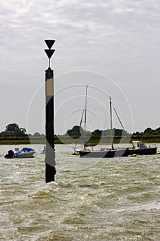 The marker beacon at the entrance to the dredged deep water channel in historic Bosham Harbour in West Sussex in the South of Engl