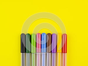 Markers of different colors on a yellow background, top view photo