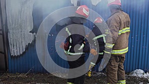 Market with carpets is on fire. Fireman gworking with chainsaw and the axe