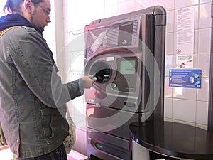 Young man using reverse vending machine