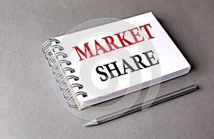 MARKET SHARE word on notebook on grey background