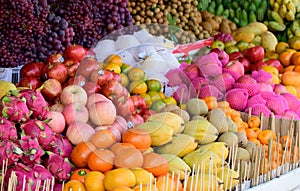 Market stall with tropicl fruits, dragon fruit, mango, apples, mandarins, joufull colors