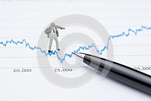 Marketing analysis or stock investment volatility concept, miniature professional businessman standing and looking, review on up