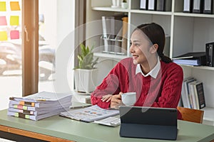 Marketing, Finance, Accounting, Planning, A female accountant holds a coffee cup and uses a laptop computer and documents, charts