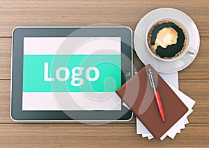 Marketing Logo Concept on tablet pc computer with cup of coffee, notebook and pen on wooden background