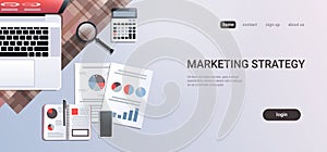 Marketing strategy concept workplace desk office stuff top angle view laptop with paper documents report finance graph