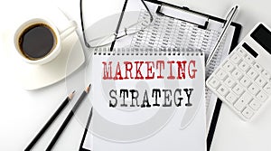 MARKETING STRATEGY text on the paper with calculator, notepad, coffee ,pen with graph