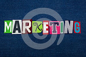 MARKETING text word collage, multi colored fabric on blue denim, sales and marketing concept