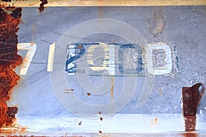 Marking of old number painted on iron plate with rust in front view