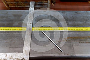 Markings metal surface for drilling holes. Worker uses tool to measure and mark on an iron surface.