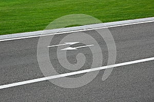 Markings road with arrows and green grass.