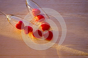 Marmalade red hearts and two glasses of champange on wooden background with sunlight. Background for Valentine`s day and photo