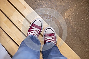 Maroon Tennis Shoes and Jeans on Wooden Bench