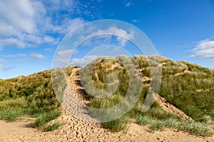 Marram grass covered sand dunes at Formby in Merseyside, with a blue sky overhead