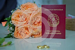 Marriage Certificate of the Republic of Azerbaijan .Yellow gold engagement rings against the background of a bouquet of