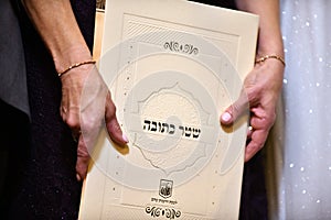 Marriage contract in the hands of the mother of the bride at a traditional Jewish wedding Hebrew Inscription - `Marriage Contract