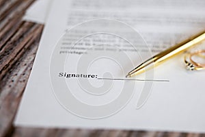 Marriage contract with two golden wedding rings and gold pen, prenuptial agreement, macro close up, sign with signanture,document,