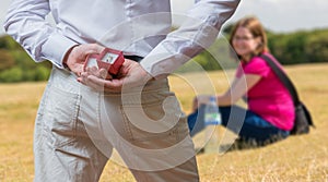 Marriage proposal concept. Man holds wedding ring behind back