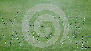 Marriage proposal in flowers on green lawn, seen from aerial drone birdseye view